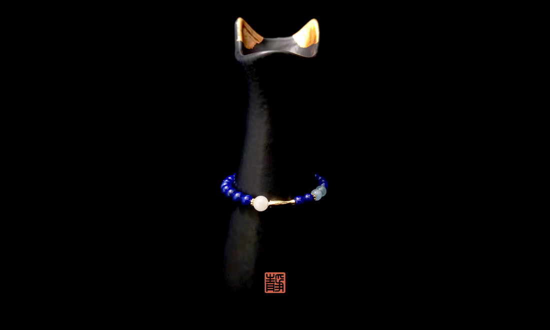 Wearable Feng Shui crystal bracelet with strawberry quartz and clear quartz beads displayed on a black ceramic stand, symbolizing personal energy signature and the balance of mind and emotions.