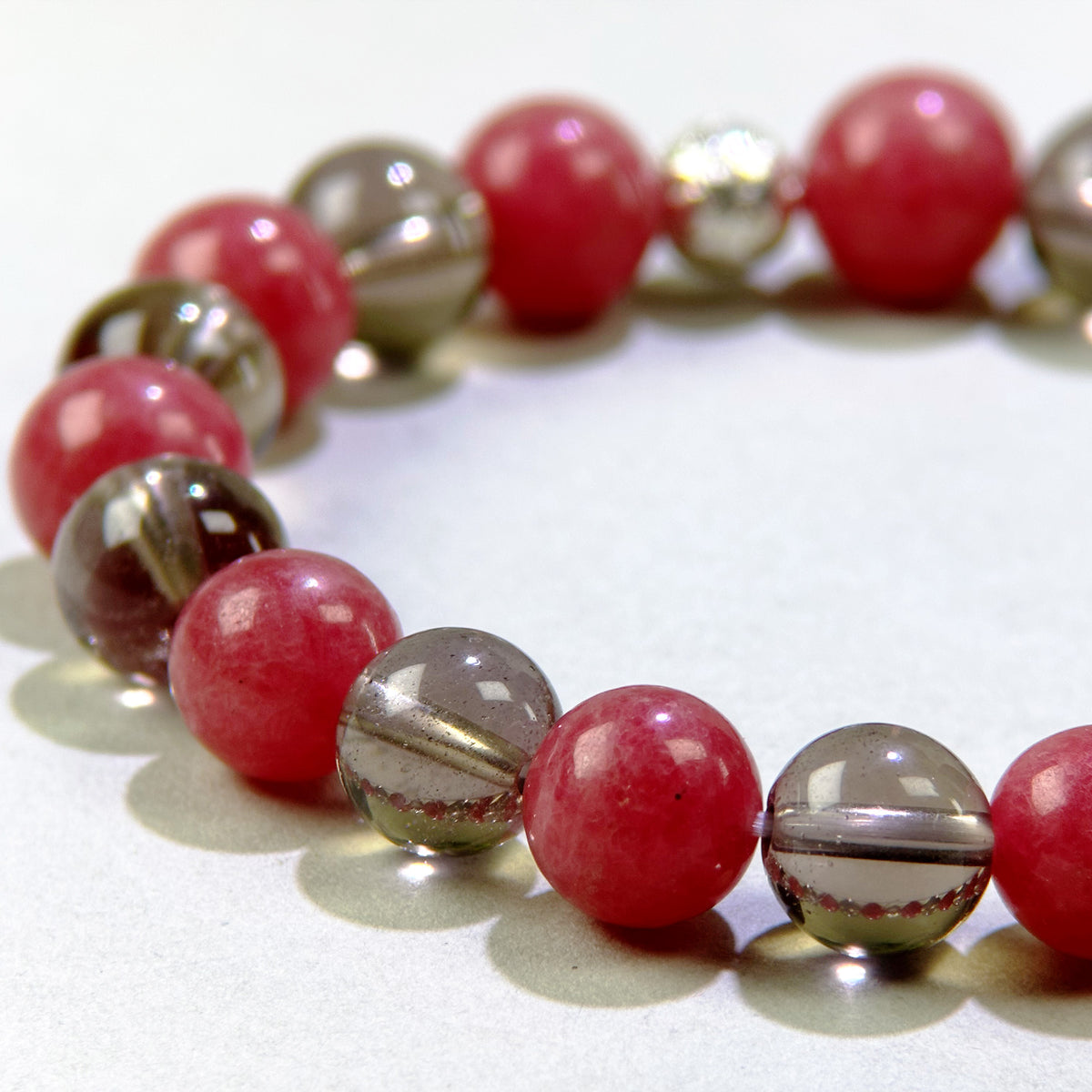 Close-up of Rhodonite and Smoky Quartz beads in a crystal bracelet for emotional healing and grounding