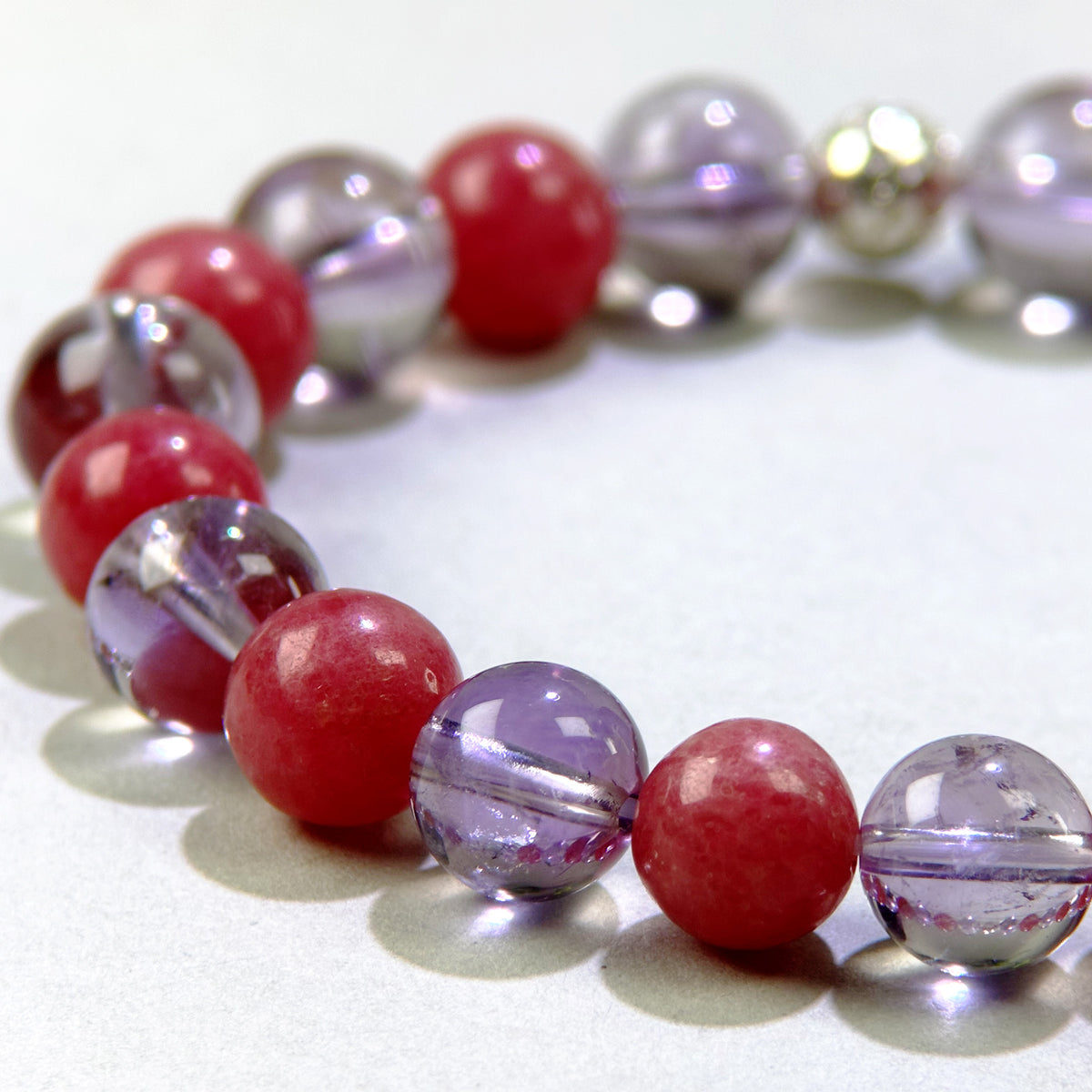 Close-up of Amethyst and Rhodonite beads in a crystal bracelet for quieter thoughts and emotional healing