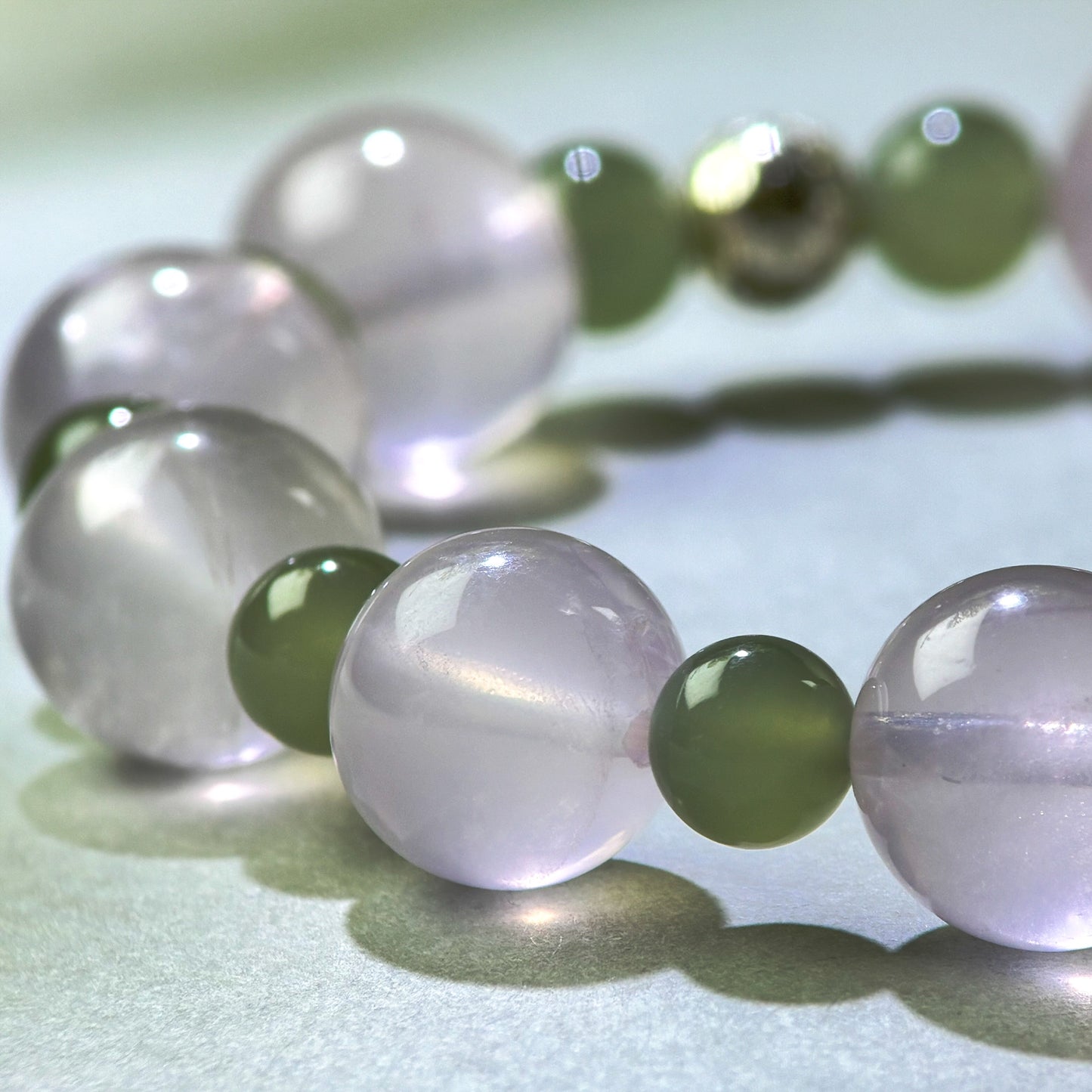 Close-up of Rose Quartz and Green Hetian Jade beads in a crystal bracelet for emotional connection
